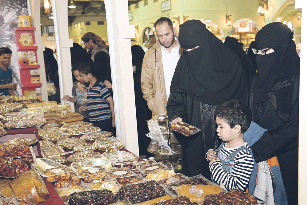 زوار يطالعون معروضات متنوعة من التمر بالمهرجان (تصوير: لطيفة الملحم)