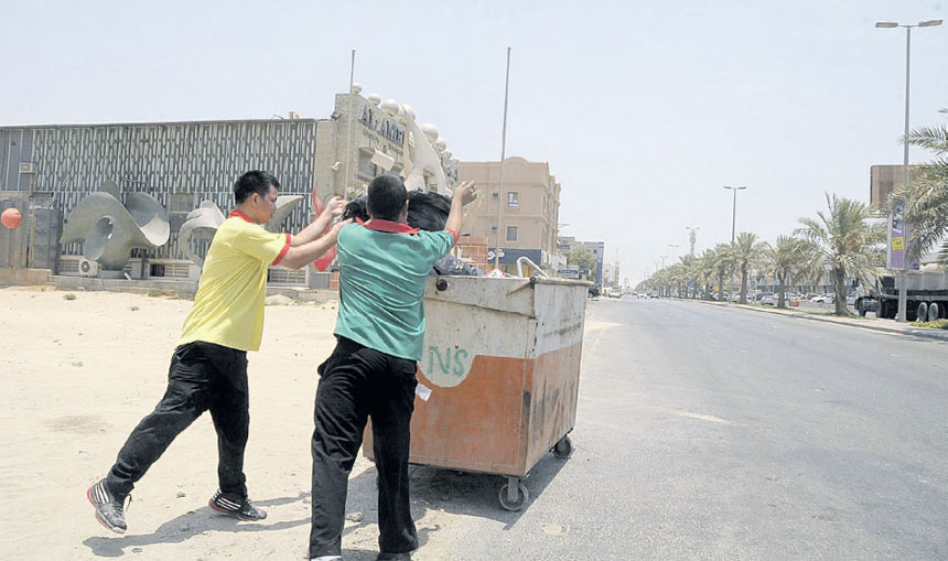 عاملان يقومان بوضع نفايات بحاوية 