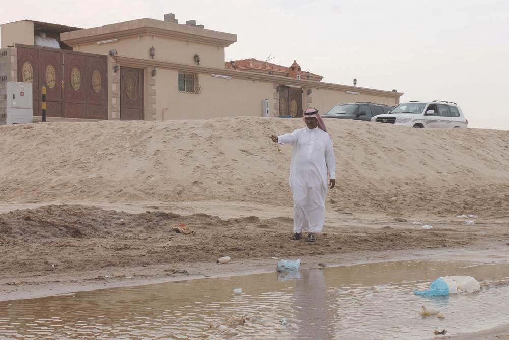 ناصر المري ينتظر سفلتة الشارع أمام منزله (تصوير: بدر الدوسري) 