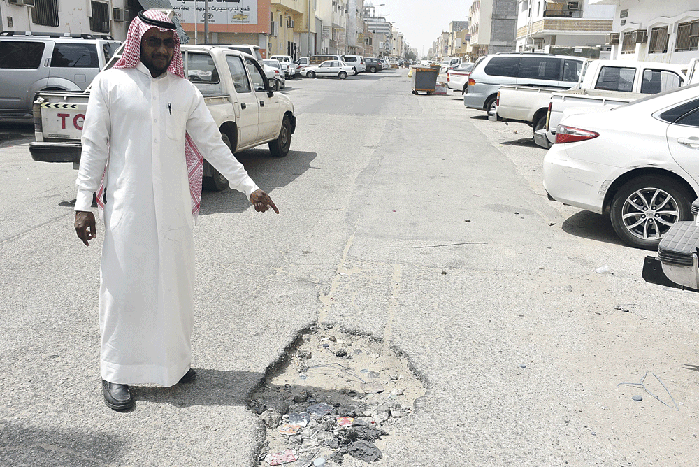 مواطن يشير إلى إحدى الحفر (تصوير: هاني الغامدي)