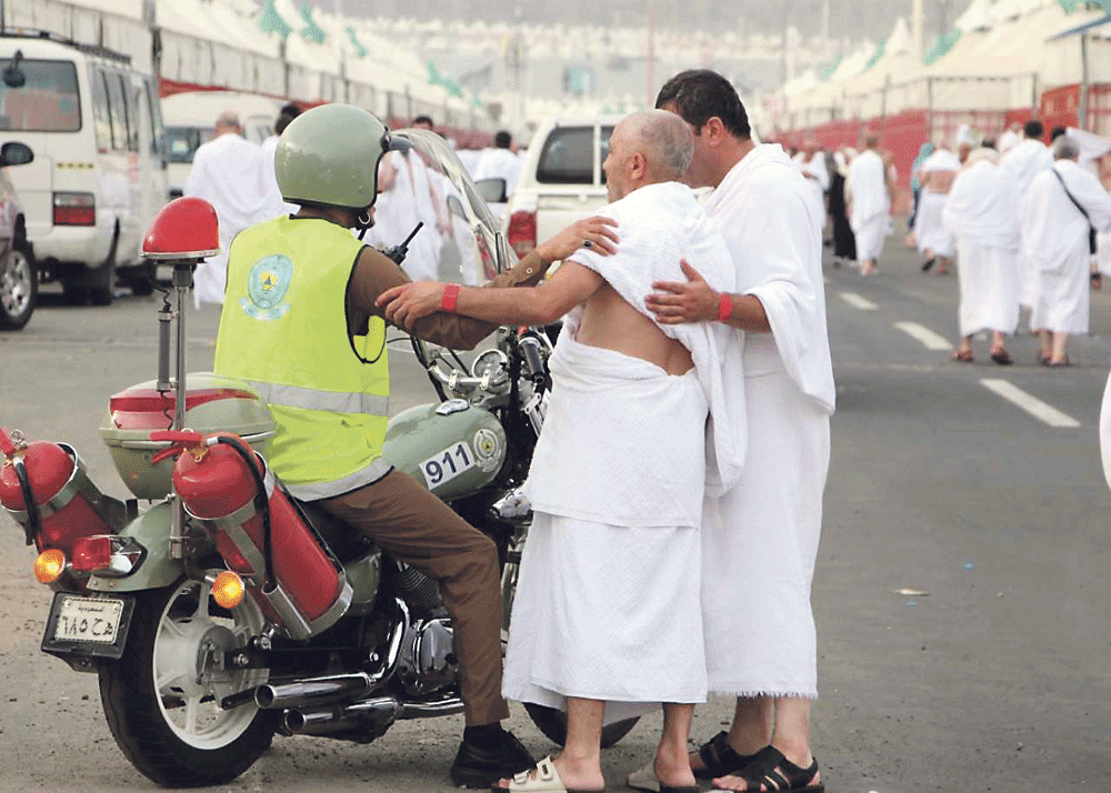 رجل دفاع مدني يحاول مساعدة حاجين بمنى (تصوير: إبراهيم السقوفي) 